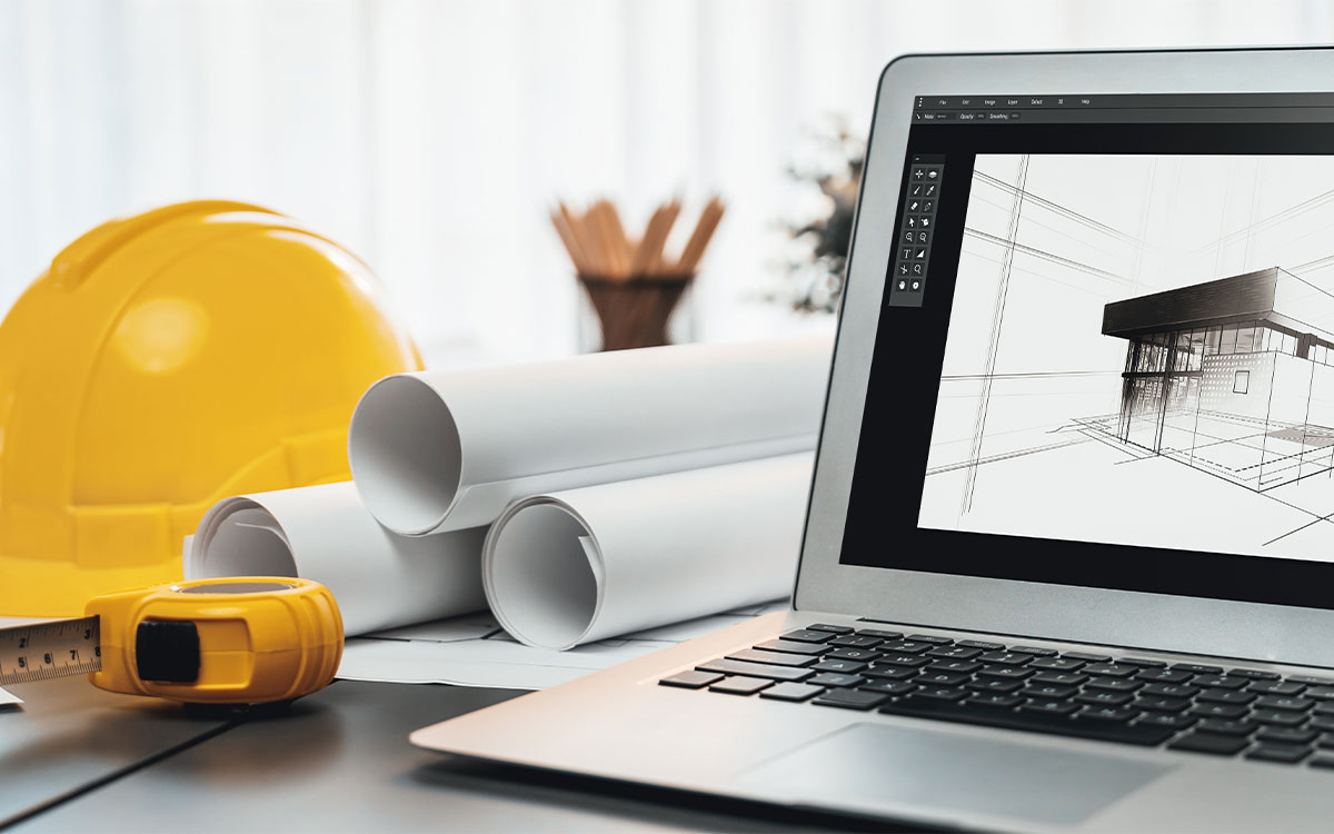 Innovative Techniken im Zimmerei Handwerk: Ein Laptop mit Software für Digitale Bauplanung steht auf einem Tisch, daneben liegt Zimmerer Ausrüstung