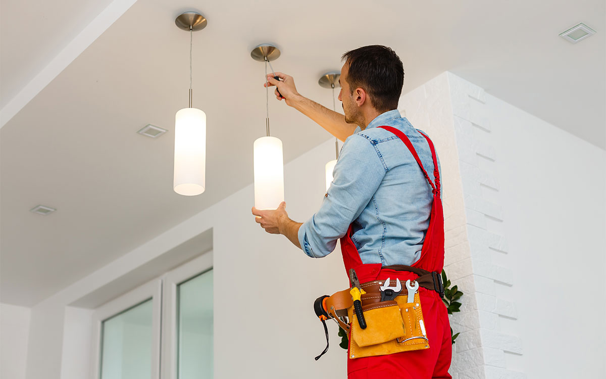 Nachhaltigkeit Handwerk Elektrotechniker: Elektroniker: Mann installiert Lampen an die Decke einer Praxis