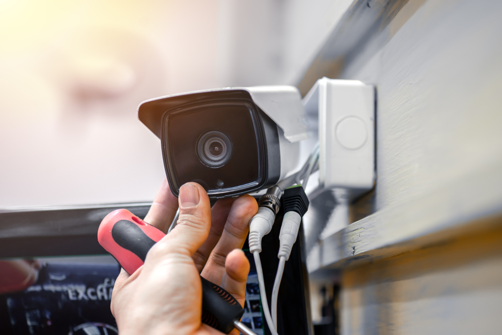 Close-up,Of,Surveillance,Camera,Installation,,Male,Hand,Holds,Cctv,Camera Sicherheit und Normen im Elektrohandwerk