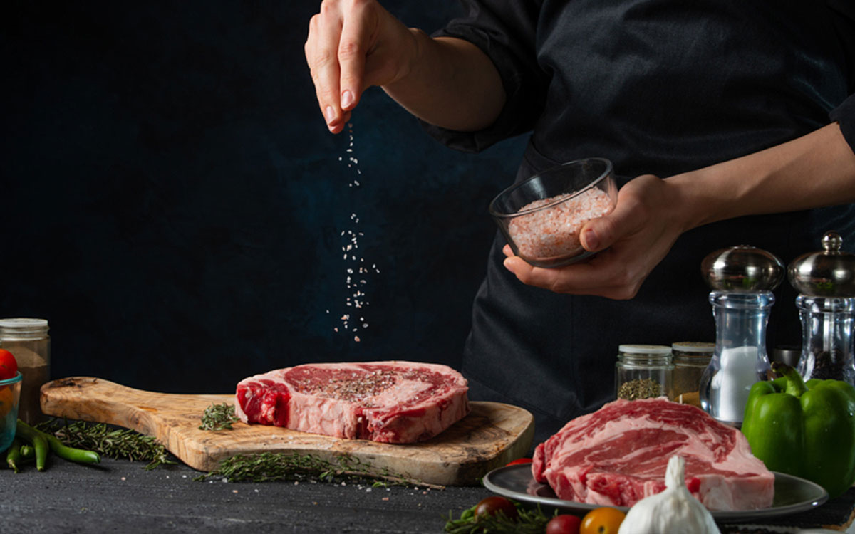 Winfood, Fleischlieferant, Hamburg, Lübeck, Thorsten Winrich - Mann streut Salz über ein Stück Fleisch