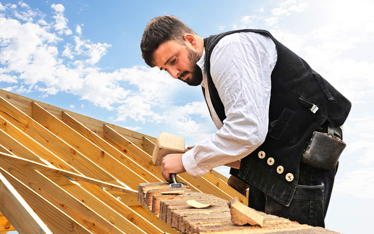 Zimmerei Werner Lübeck, Manuel Werner, Zimmereiarbeiten - Mann / Zimmerer arbeitet an einem Holzdach